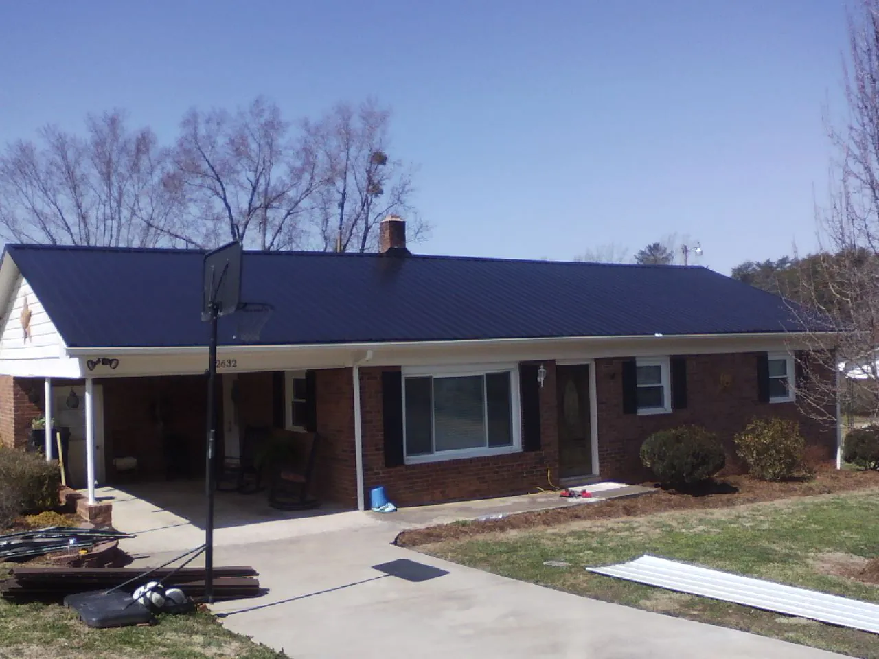 Finished dark blue metal roof on a brick ranch with a carport in Bradley